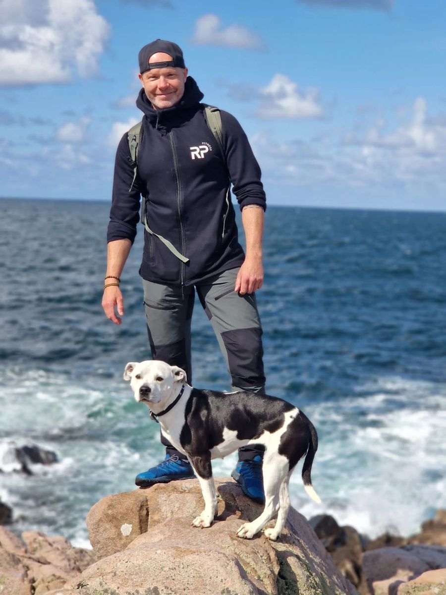 Rich Palmer outdoors with his dog on a rocky shore